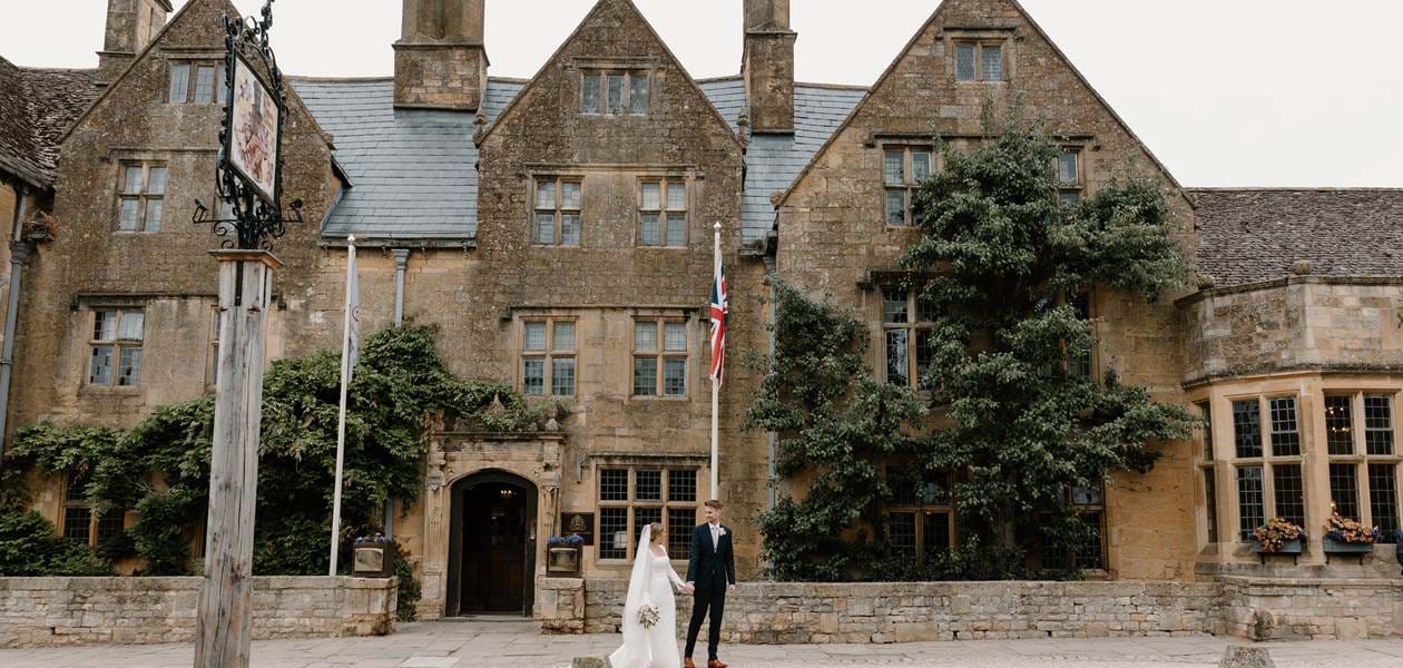 Happy couple on their wedding day posing in front of The Lygon Arms